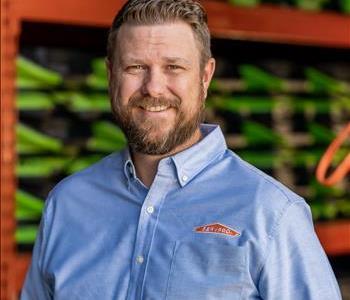 Jeremy has sandy brown hair and a sandy brown beard. He is wearing a blue SERVPRO shirt.